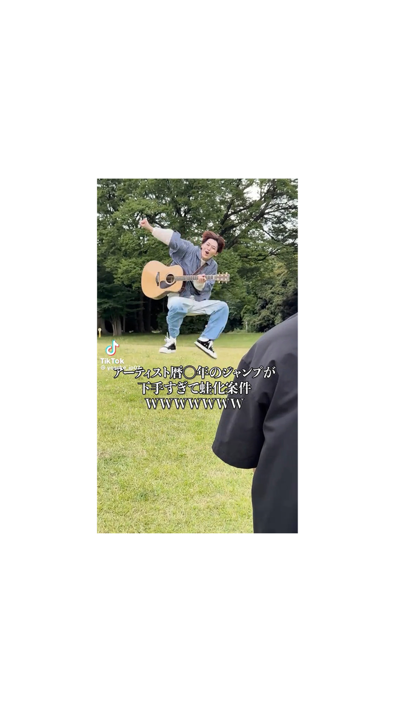 ギターを抱えて公園でジャンプするYOSUKE。ジャンプをいじるテロップが入った日本向けTikTok動画